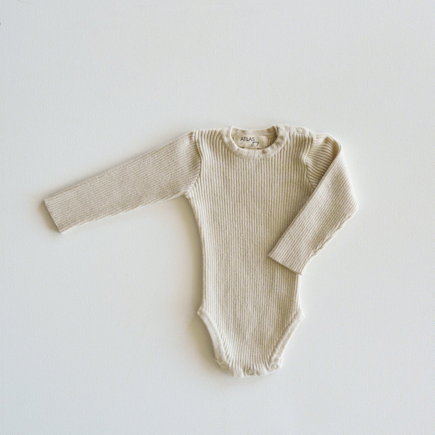 Beige ribbed baby onesie on a white background