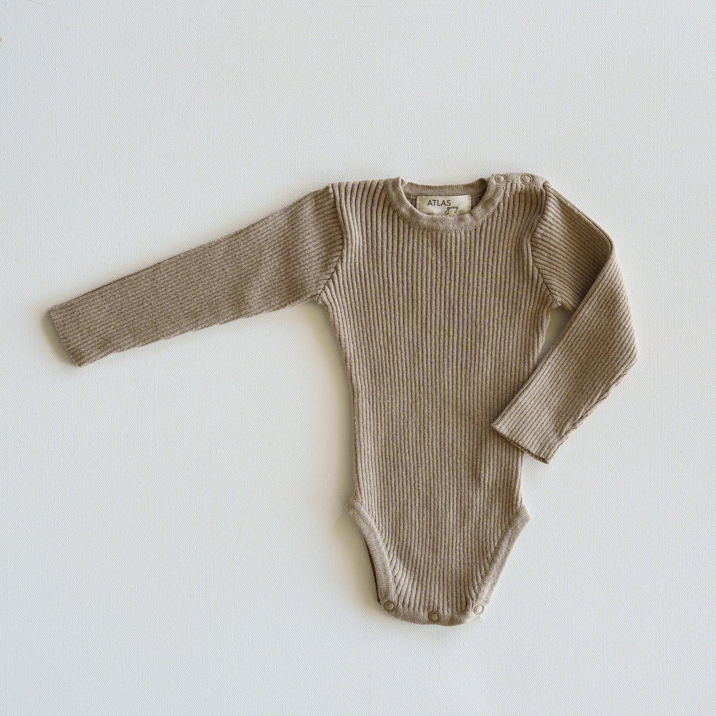 Brown ribbed baby onesie on a light gray background