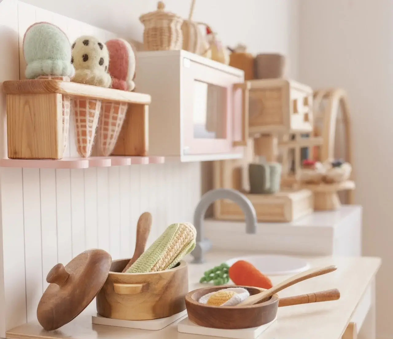 a wooden pots and pans play set with crochet foods in a wooden play kitchen