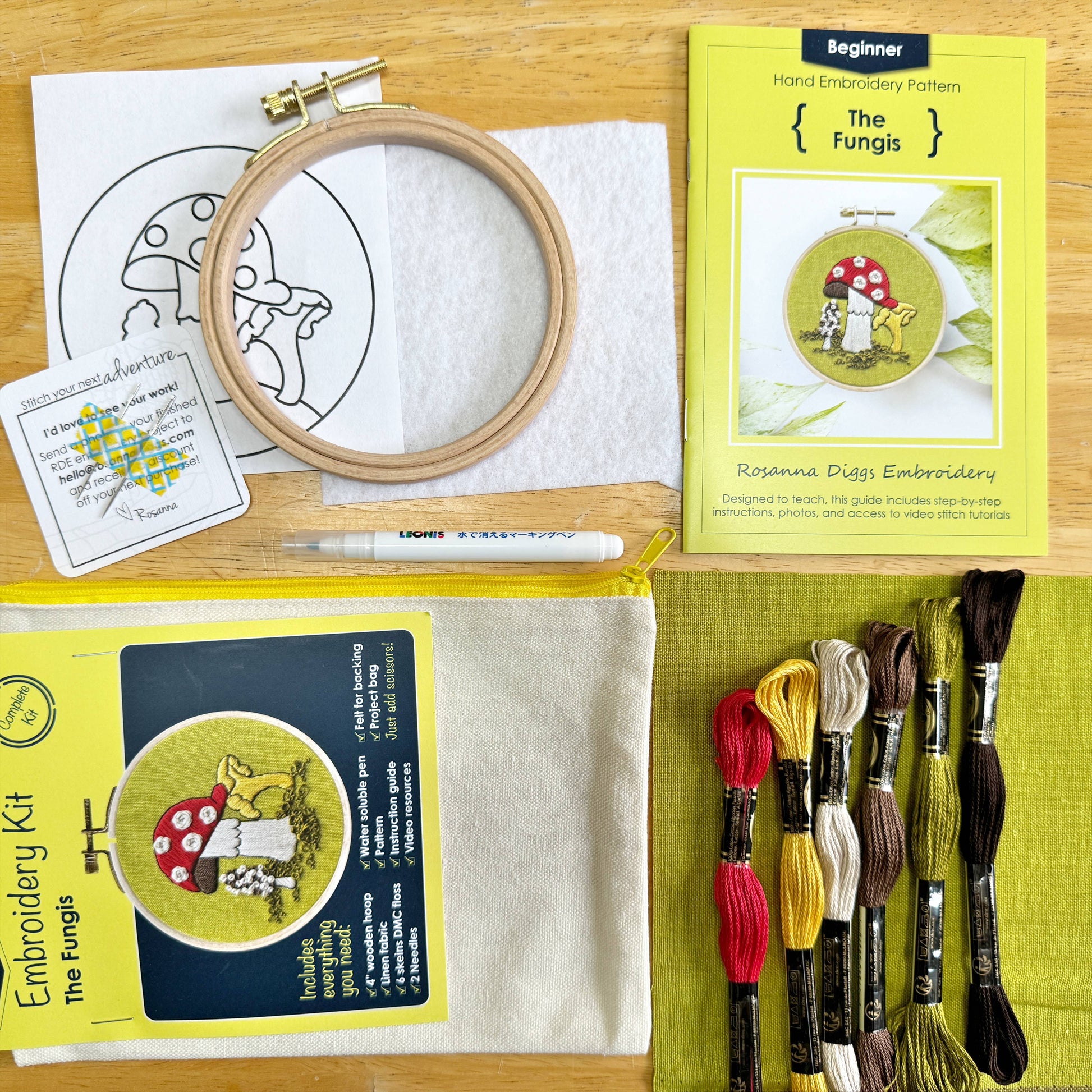 Embroidery kit with hoop, thread, pattern cards, and fabric on a wooden surface