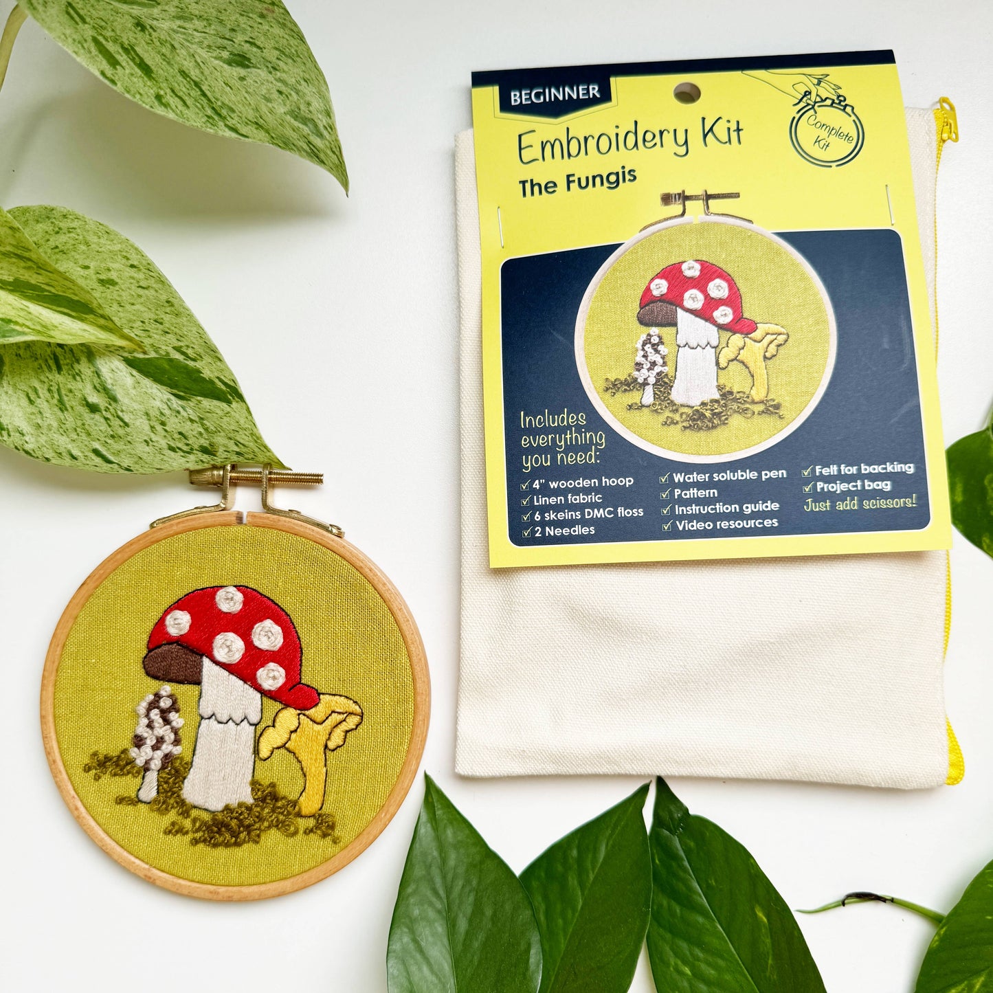 Embroidery kit with mushroom design and packaging on a white background with leaves.