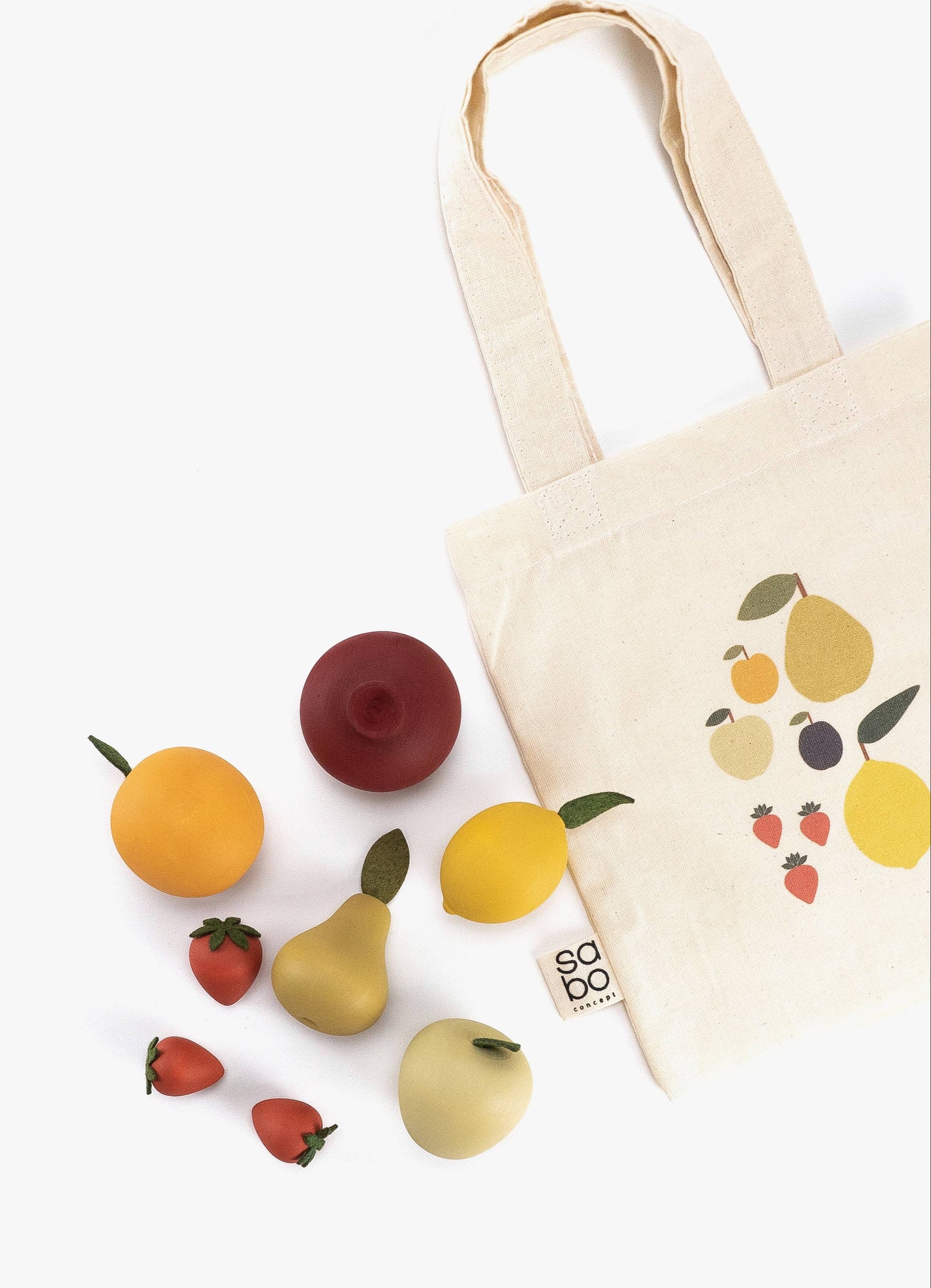 an assortment of wooden fruits next to a cotton tote bag