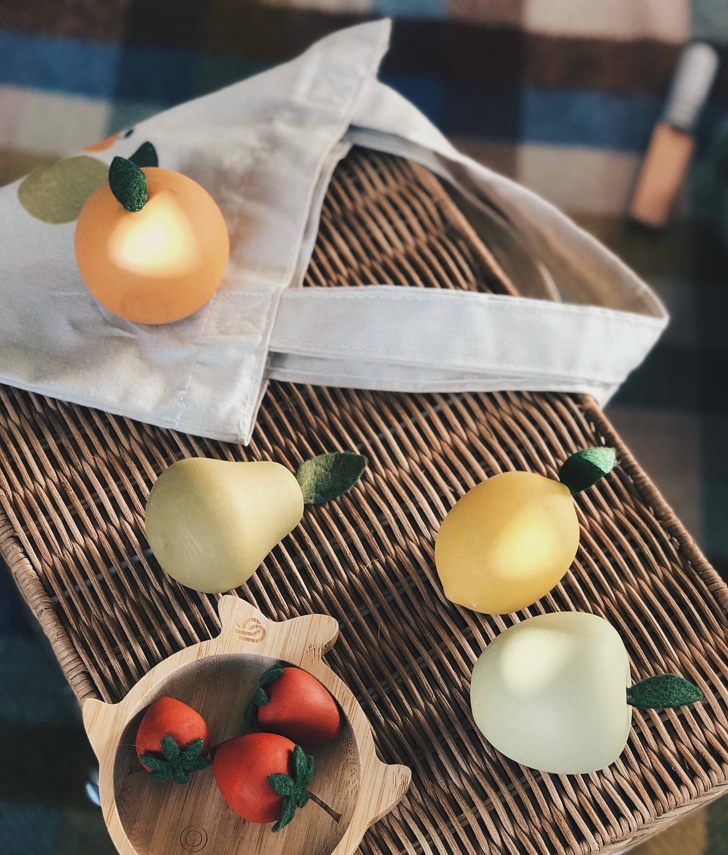 wooden toy fruits laying on a wicker basket with a cotton totebag