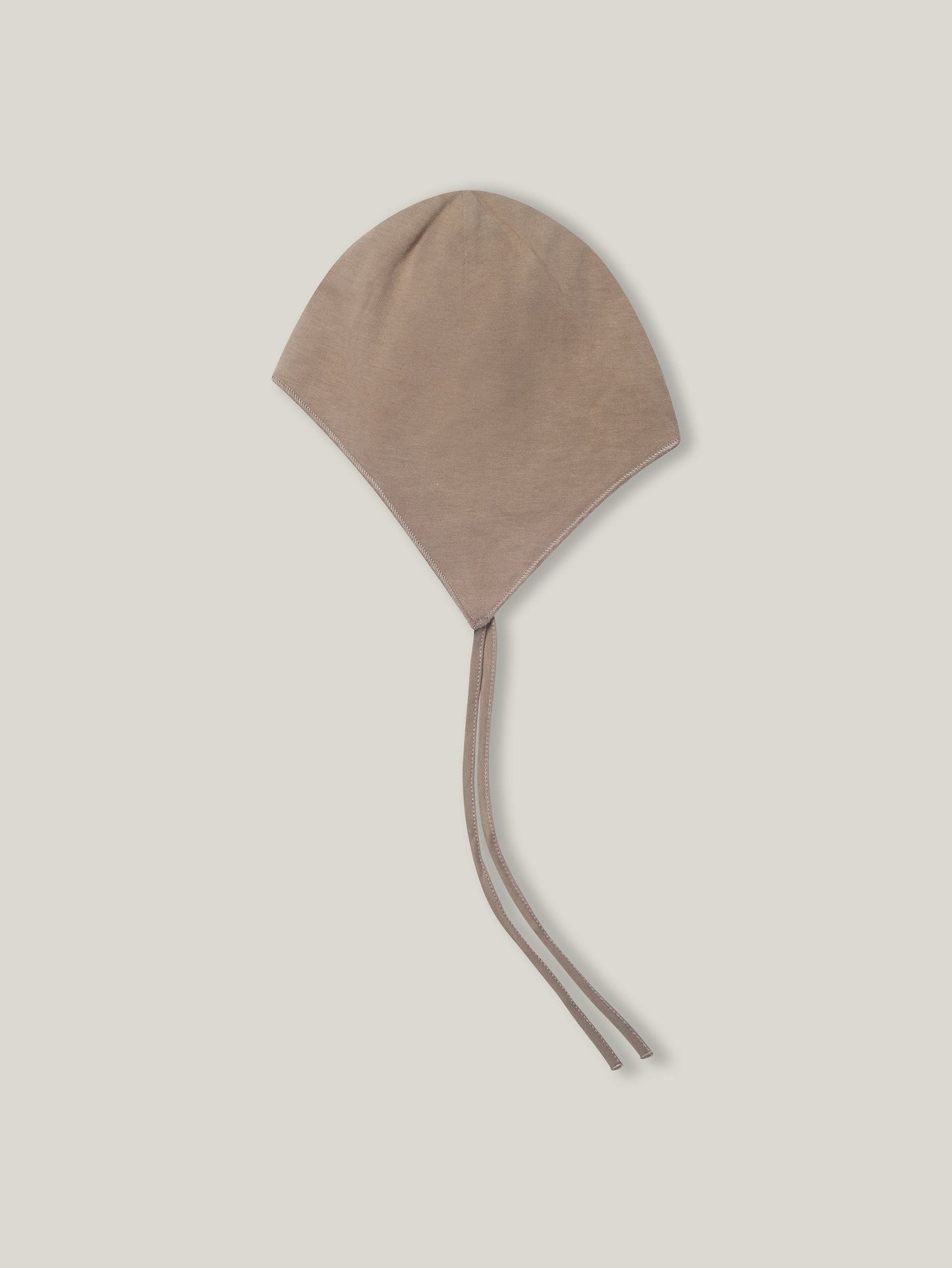 Beige baby bonnet on a light beige background