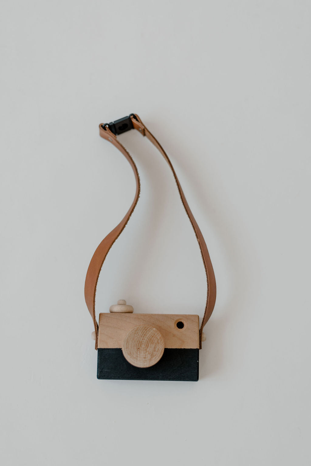 Wooden camera-shaped purse with a strap on a light background
