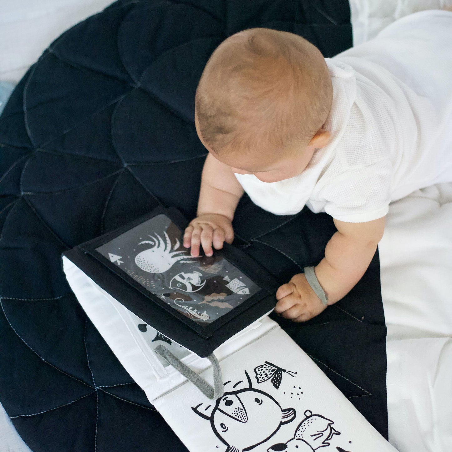 Baby interacting with a toy on a black and white mat
