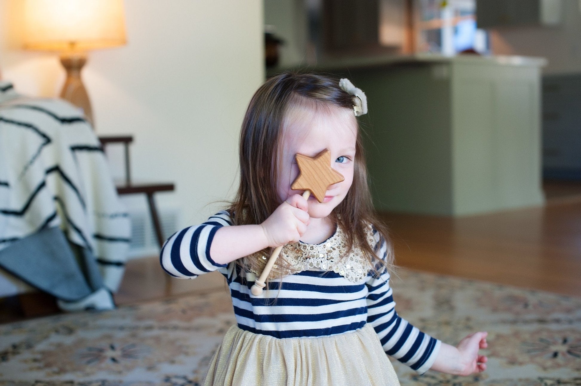 Young girl holding a star-shaped cookie in a living room.