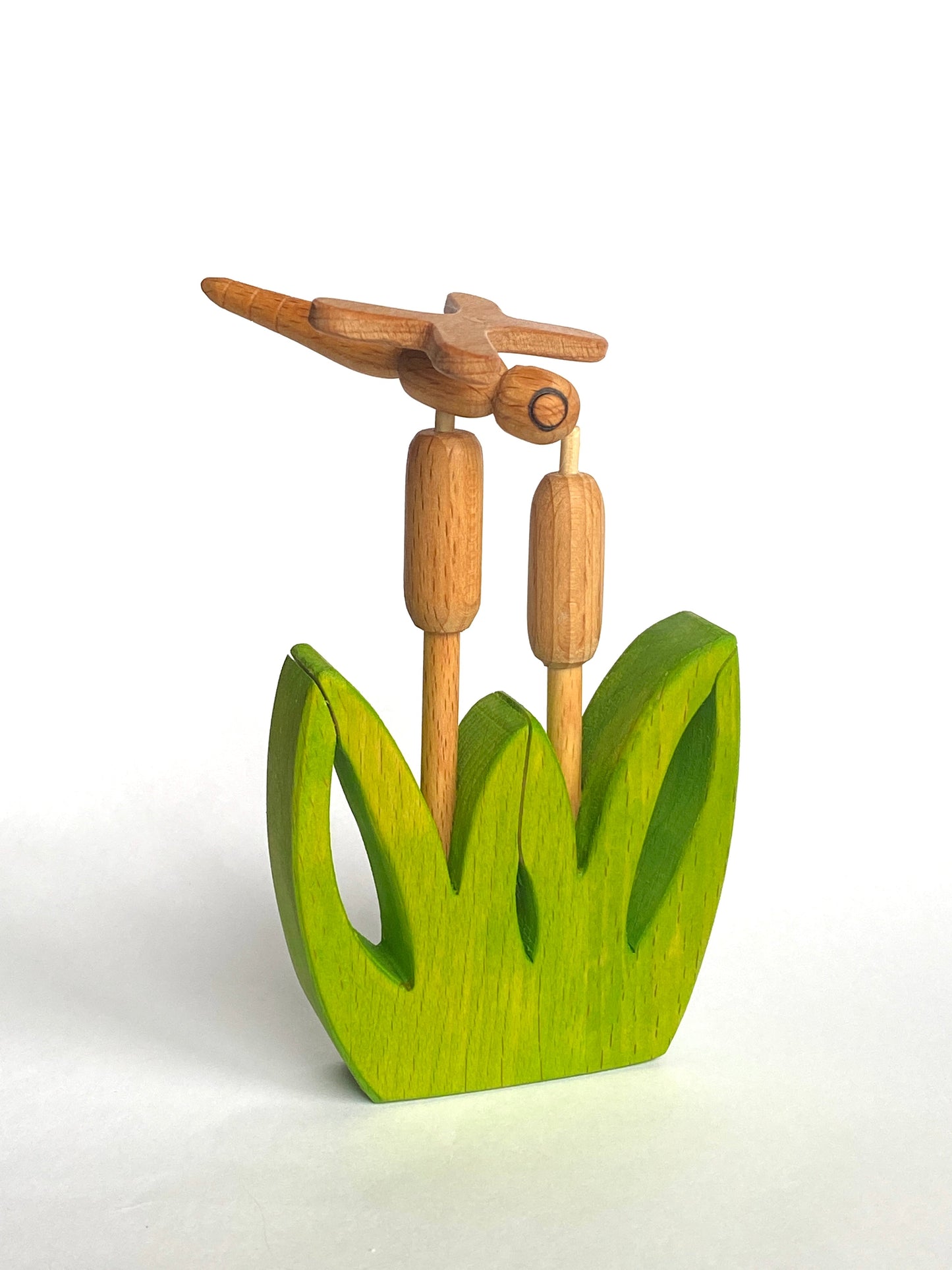 Wooden sculpture of a bird on a branch with green base on a white background
